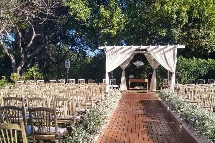Altar de cortinas claras e cadeiras montadas no jardim