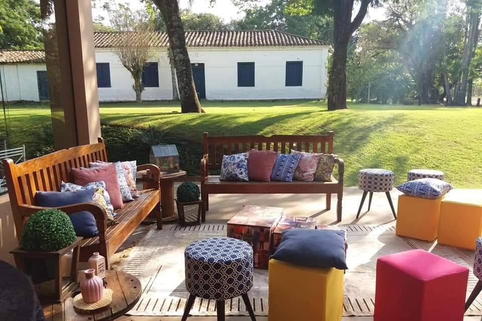 Bancos e poltronas à sombra, com a fachada da casa ao fundo
