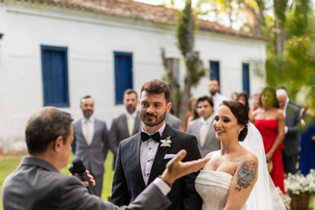 Celebrante e noivos diante da casa de janelas azuis