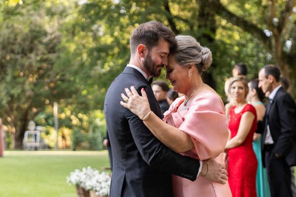 O noivo abraça a mãe no gramado