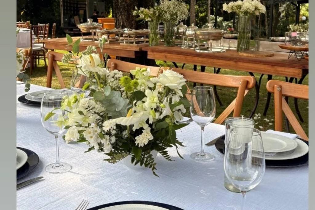 Arranjo de flores brancas e taças na mesa dos convidados