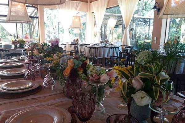Mesa posta no salão, com flores e taças